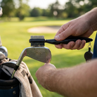 Golfer cleaning an iron face with a groove brush
