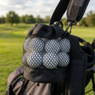 Mesh golf ball pouch clipped to a bag with golf balls